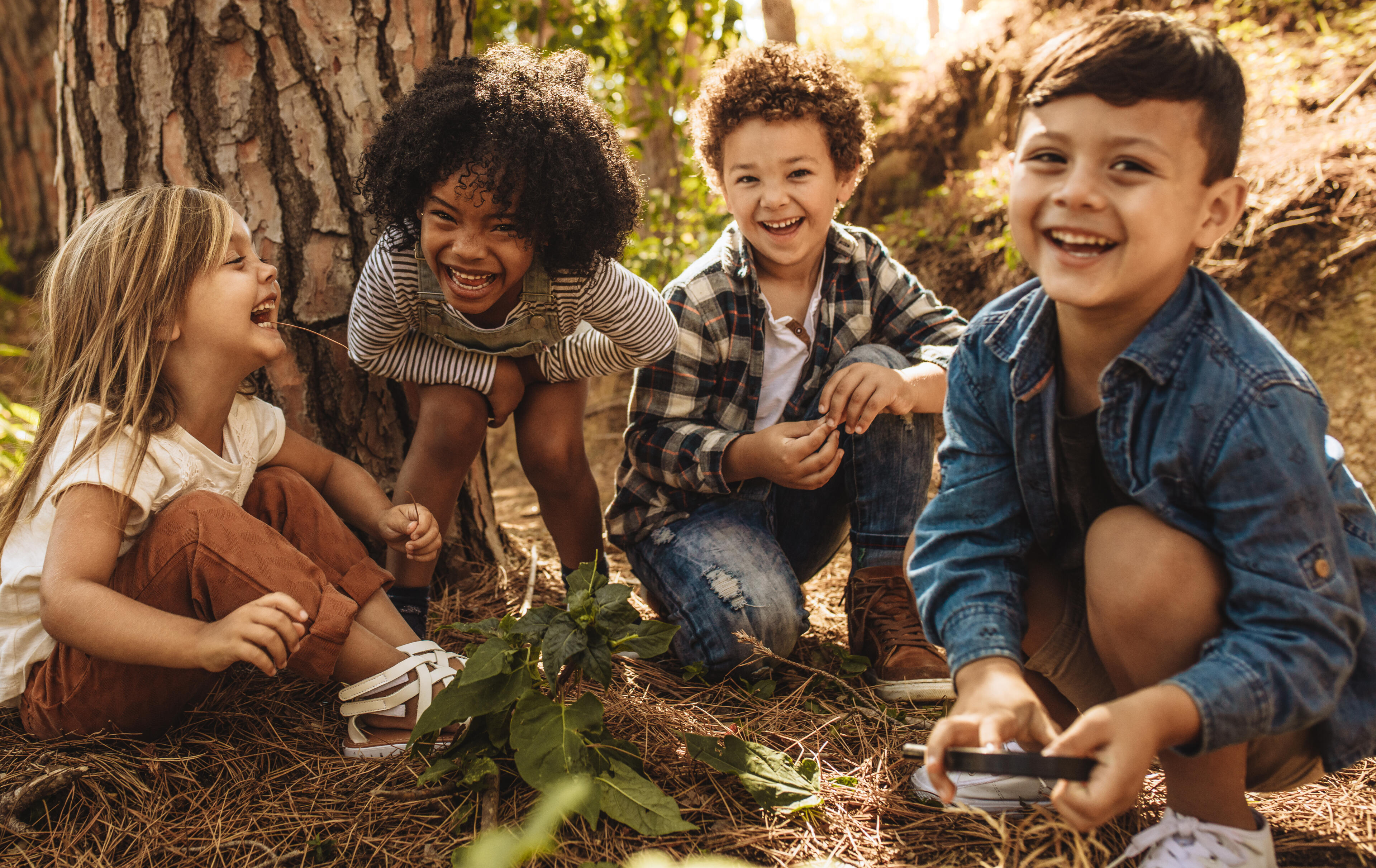 Four elementary school children having fun by laughing while out in nature.